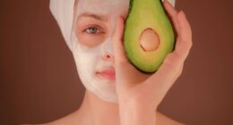 woman with white face mask holding green fruit