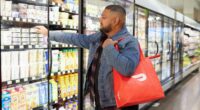 a man in a grocery store picking up a bag