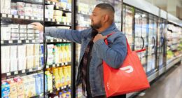 a man in a grocery store picking up a bag