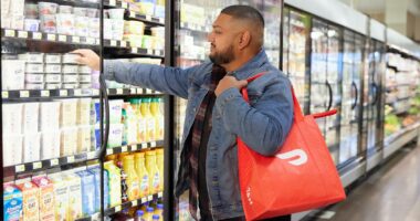 a man in a grocery store picking up a bag
