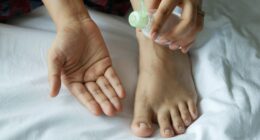 a person with a bottle on their foot on a bed