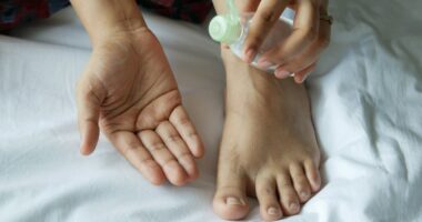 a person with a bottle on their foot on a bed