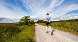 man running on road near grass field
