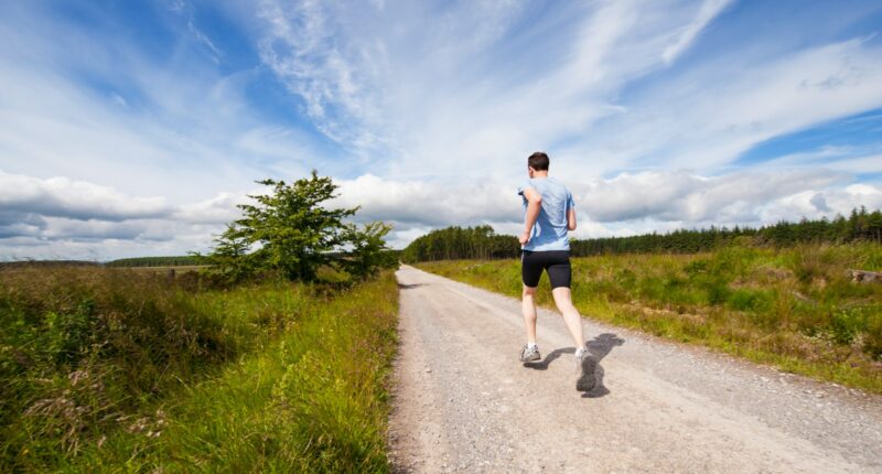 man running on road near grass field